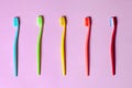 Top view on many tooth brushes of different vibrant colors laying down on lilac pink background. Royalty Free Stock Photo