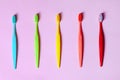 Top view on many tooth brushes of different vibrant colors laying down on lilac pink background. Royalty Free Stock Photo