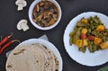 Top view of matar paneer mix veg, mushroom soup and roti Indian bread over black background.