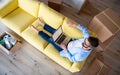 Top view of mature man sitting on sofa in unfurnished house, using laptop. Royalty Free Stock Photo