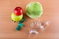 Top view on measuring tape, vacuum massagers, apples and cabbage on wooden table