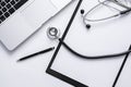 Top view of medical doctor table with stethoscope, clipboard, pen and laptop on white desk Royalty Free Stock Photo