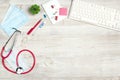 Top view medical workplace with stethoscope, keyboard, thermometer, mask, plant and supplies on white wooden desk