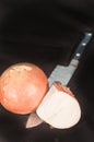 Whole and halve yellow onion with a chef`s knife`s blade