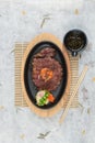 Top view of medium rare wagyu steak topping with mince carrot on hot plate and wooden plate served with potato salad, ponzu sauce. Royalty Free Stock Photo