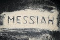 Top view of MESSIAH word written on white sand