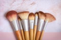 Top view of messy used eco-friendly makeup brushes with bamboo handles on white and pink background with traces of cosmetic makeup Royalty Free Stock Photo