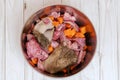 Top view of metal pet bowl with chicken necks, beef meat, paunch and carrot pieces. Royalty Free Stock Photo