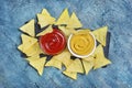 Top view on mexican nachos chips with spicy red and cheese sauce or dip in white bowls Royalty Free Stock Photo