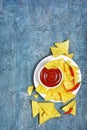 Top view on mexican nachos chips with spicy red sauce or dip in white bowl and hot chilli pepper Royalty Free Stock Photo