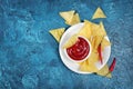 Top view on mexican nachos chips with spicy red sauce in white bowl and hot chilli pepper Royalty Free Stock Photo