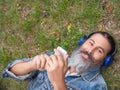 Top view of a middle aged man enjoying the music while lying on the grass in city park. Royalty Free Stock Photo