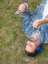 Top view of a middle aged man enjoying the music while lying on the grass in city park. Vertical photo. Royalty Free Stock Photo