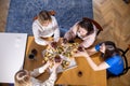 Top view of middle-aged women relatives sitting at table, talking, holding pieces of pizza, glasses of wine at home.