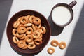 Milk in a brown ceramic cup and small dry bagels for kids on white wooden background. First solid finger food for baby. Healthy me Royalty Free Stock Photo