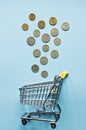 Top view mini shopping cart with Coins on blue table. business, finance, online shopping and money Saving for the future
