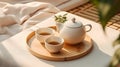 Top view of minimal, beautiful white ceramic teapot, two cups, candle on brown wooden tray on cream tablecloth in sunlight Royalty Free Stock Photo