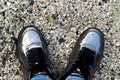 Top view of mirror shoes on a gray stone. The minimal style. Sneakers on the background of small pebbles