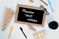 Top view of MISSION AND VALUES written on a blackboard. Pencil cup, glasses, color marker and Wood block stacking as step stair