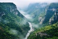 top view of misty canyon with winding river at cliff bottom