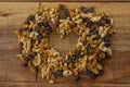 A top view of mix nuts. Raisins and a variety of dried fruits, grouped together forming a heart on a wood texture