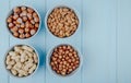 top view of mixed nuts in shell and without shell in bowls almond hazelnuts and peanuts on blue background with copy space