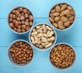 top view of mixed nuts in shell and without shell in bowls almond hazelnuts and peanuts on blue background