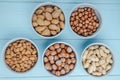 top view of mixed nuts in shell and without shell in bowls almond hazelnuts and peanuts on blue background