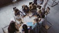 Top view of mixed race business team sitting at the table at loft office and working. Woman manager brings the document. Royalty Free Stock Photo