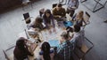 Top view of mixed race business team sitting at the table at loft office and working. Woman manager brings the document. Royalty Free Stock Photo