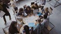 Top view of mixed race business team sitting at the table at loft office and working. Woman manager brings the document.