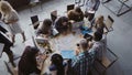 Top view of mixed race business team sitting at the table at loft office and working. Woman manager brings the document. Royalty Free Stock Photo