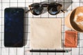 Top view of mobile phone with blank screen with coffee cup,brown sugar,sunglasses,pencil tissue paper on white table cloth.Mock u