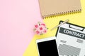 Top view mock up of contract, pen and black screen tablet, notebook with roses on pink yellow pastel color with copy space. Royalty Free Stock Photo
