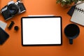 Top view of digital tablet, camera, coffee cup and notebook on orange background. Royalty Free Stock Photo