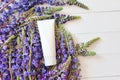 Mock-up of white squeeze bottle plastic tube for branding of medicine or cosmetics and lupine flowers on a white wooden background