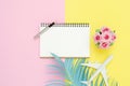 Top view mockup of blank paper notebook, pen, pastel leaf, roses and plane on pink yellow pastel color screen. Royalty Free Stock Photo