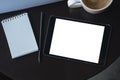 Top view mockup image of a black tablet pc with blank white desktop screen with notebook and coffee cup Royalty Free Stock Photo