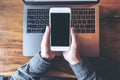 Top view mockup image of business woman holding mobile phone with blank white screen with latop on wooden table