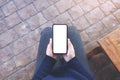 Hands holding black mobile phone with blank white screen horizontally with coffee cup on wooden table in vintage Royalty Free Stock Photo