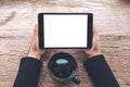 Top view mockup image of hands holding black tablet pc with blank white screen and coffee cup on vintage wooden table Royalty Free Stock Photo