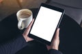 Hands holding black tablet pc with white blank screen and coffee cup on table background Royalty Free Stock Photo