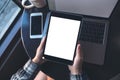 Top view mockup image of hands holding black tablet pc with white blank screen and laptop , coffee cup on wooden table background Royalty Free Stock Photo