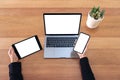 Top view mockup image of a hands holding mobile phone , black tablet and laptop with blank white screen Royalty Free Stock Photo