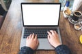 Hands using and typing on laptop with blank white desktop screen and coffee cups on wooden table Royalty Free Stock Photo