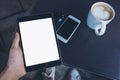 Top view mockup image of a man`s hands holding black tablet pc with blank white screen ,coffee cup , mobile phone Royalty Free Stock Photo