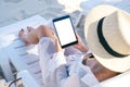 A woman holding a black tablet pc with blank desktop screen while laying down on beach chair on the beach Royalty Free Stock Photo