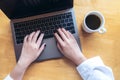 Top view mockup image of woman`s hands using and typing on laptop with blank white desktop screen and coffee cup on wooden table Royalty Free Stock Photo