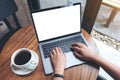 Top view mockup image of a woman using and typing on laptop with blank white desktop screen on wooden table Royalty Free Stock Photo