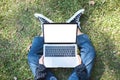 A woman using and typing on laptop with blank white screen while sitting in the outdoors Royalty Free Stock Photo